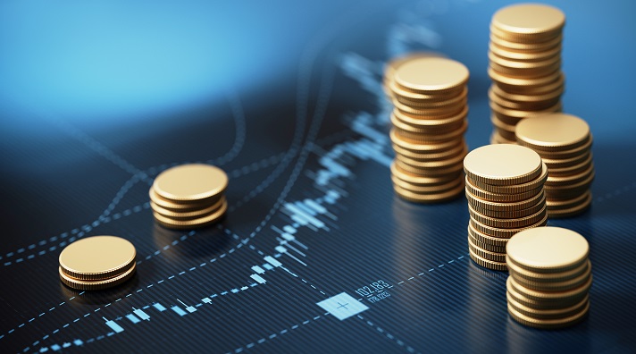 Stacks of gold coins placed on a financial chart with data points and trends.