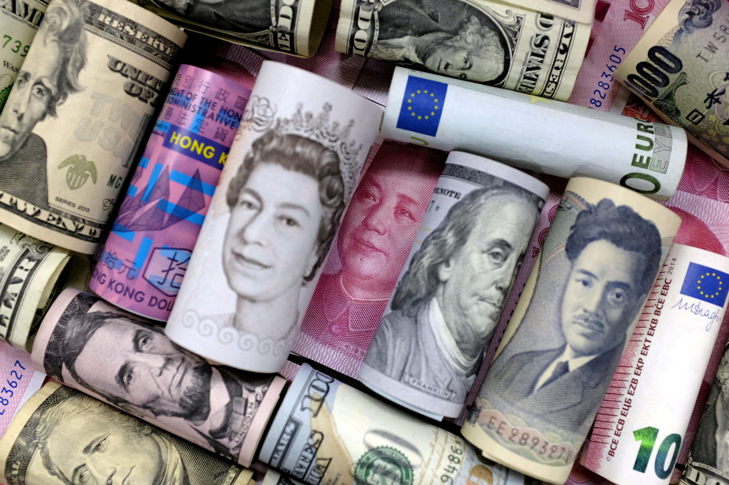 Rolled banknotes from various countries, including US dollars, British pounds, euros, and Chinese yuan.
