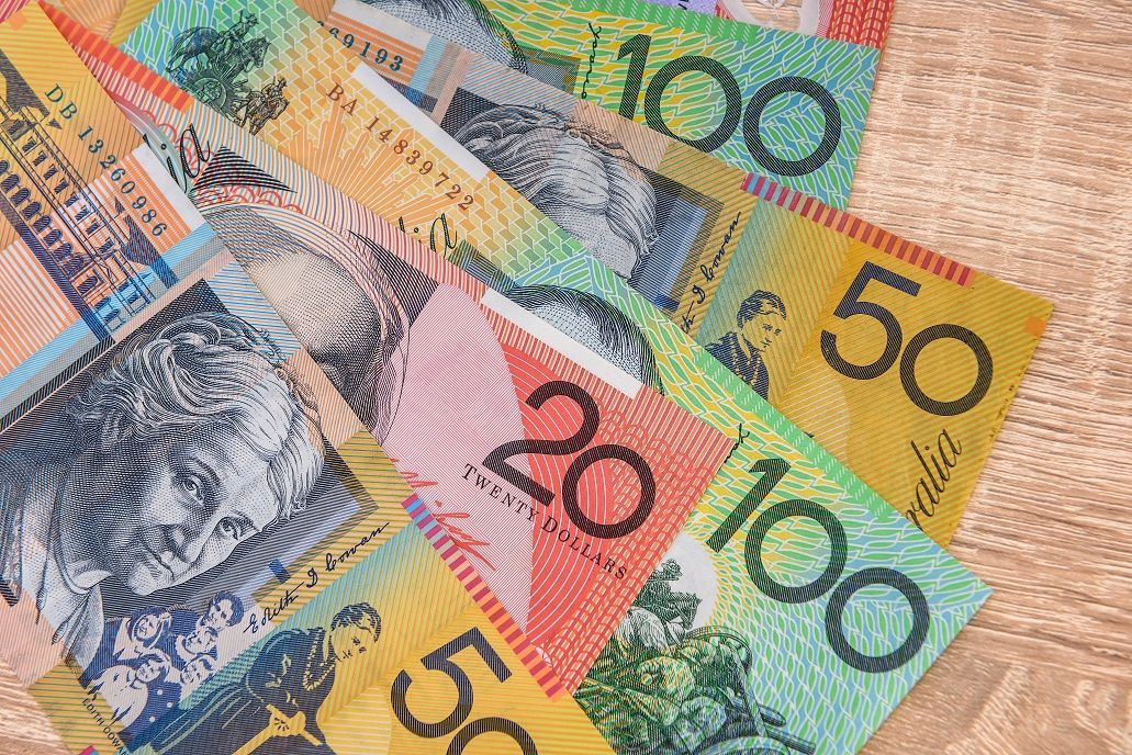 A collection of colorful Australian dollar banknotes spread out on a wooden surface.