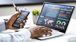 A person analyzing financial charts and data on a laptop and smartphone.